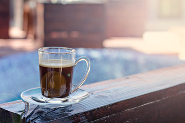 A cup of espresso and a pool in the background. Morning coffee. Summer Breakfast.
