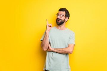 Man with beard and green shirt thinking an idea pointing the finger up