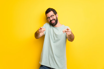 Man with beard and green shirt points finger at you while smiling
