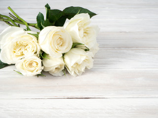 Obraz na płótnie Canvas White roses on a white wooden table