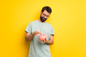 Man with beard and green shirt taking a piggy bank and happy because it is full