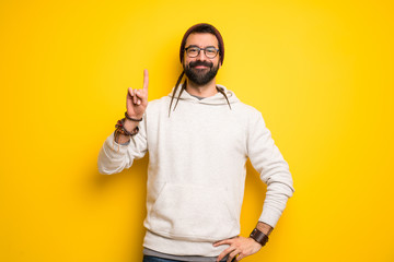 Hippie man with dreadlocks showing and lifting a finger in sign of the best