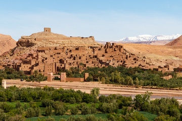 Fototapeta na wymiar Fortified city of Ait Benhaddou along the former caravan route between the Sahara and Marrakech in Morocco with snow covered Atlas mountain range in background