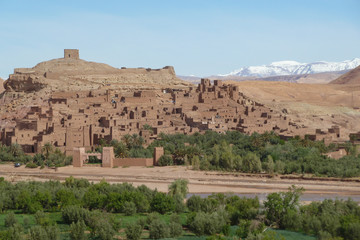 Fortified city of Ait Benhaddou along the former caravan route between the Sahara and Marrakech in Morocco with snow covered Atlas mountain range in background