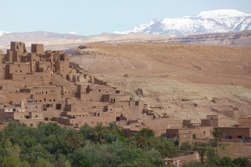 Fortified city of Ait Benhaddou along the former caravan route between the Sahara and Marrakech in Morocco with snow covered Atlas mountain range in background