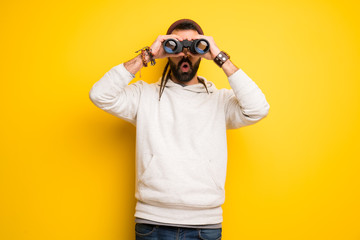 Hippie man with dreadlocks and looking in the distance with binoculars