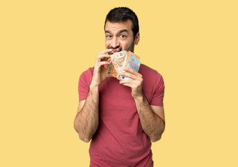 Man taking a lot of money showing a sign of silence gesture on isolated yellow background