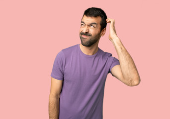 Fototapeta na wymiar Handsome man having doubts while scratching head on isolated pink background