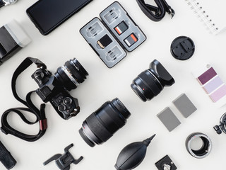 top view of work space photographer with digital camera, flash, cleaning kit and memory card on white table background. - obrazy, fototapety, plakaty
