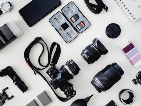 top view of work space photographer with digital camera, flash, cleaning kit and memory card on white table background.