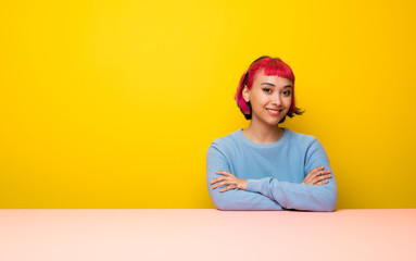 Young woman with pink hair keeping the arms crossed in frontal position