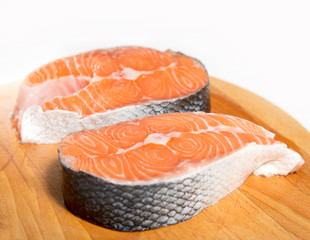 Close up two pieces of fresh fish meat salmon on a wooden board on a white background.