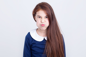 Portrait of a girl who puffed up her cheeks in anger and displeasure while standing on a light...