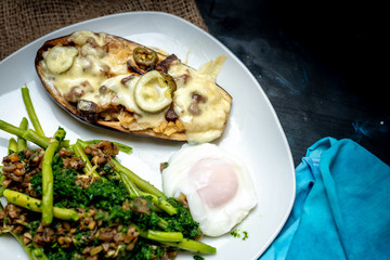 Fototapeta na wymiar Baked eggplant with cheese and mushrooms, next to green legumes and spinach and fried egg