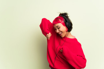 Young woman with red sweater listening to music with headphones and dancing