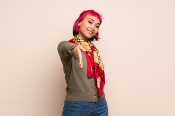 Young woman with pink hair over yellow wall shaking hands for closing a good deal
