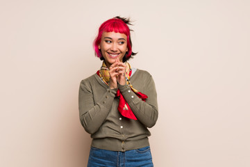 Young woman with pink hair over yellow wall scheming something