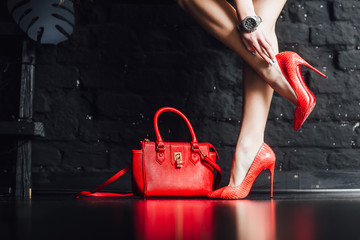 Female legs in red maroon high heel shoes goes on black background. - obrazy, fototapety, plakaty