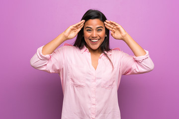 Young Colombian girl over purple wall with surprise expression