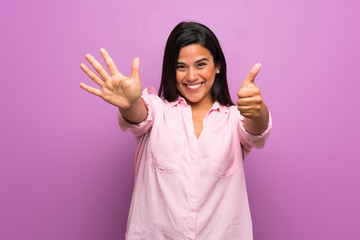 Young Colombian girl over purple wall counting six with fingers