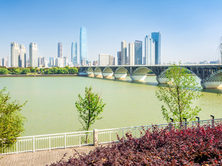 Bridge across Xiang river in Changsha, capital of Hunan province of China, leading to Orange Isle, with tall downtown buildings in the background.