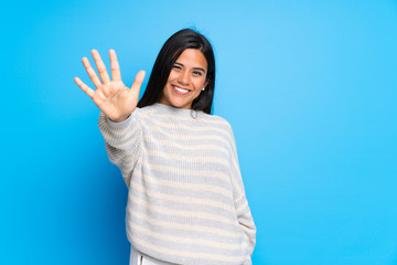 Young Colombian girl with sweater counting five with fingers