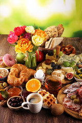 breakfast on table with bread buns, croissants, coffe and eggs