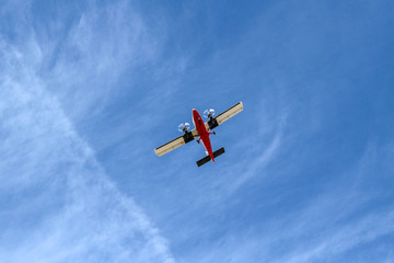 Small Airplane Flying at Low Altitude Under Blue Sky Viewed from Below