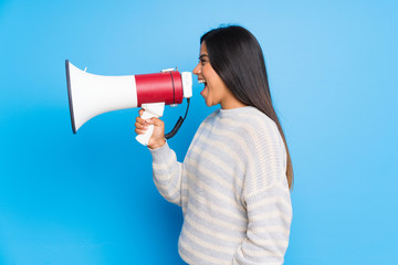 Young Colombian girl with sweater shouting through a megaphone