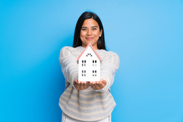 Young Colombian girl with sweater holding a little house
