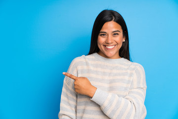 Young Colombian girl with sweater pointing finger to the side