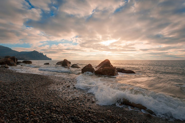 Coastal landscape. Rocks & stones at the seashore. Beautiful sunrise over pebble sea beach.