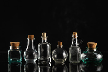 Glass bottles of different shapes and sizes on a black background.