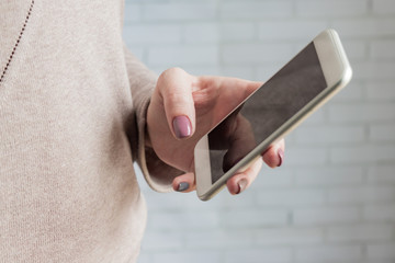 Woman holding white smatphone in her hand with trendy manicure. Selective focus