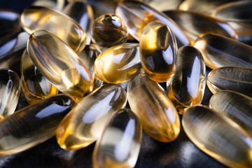 yellow fish oil capsules, omega 3, on a black background