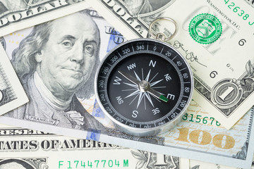 Compass and pile of US dollar money banknote, investment, financial crisis or economic direction concept