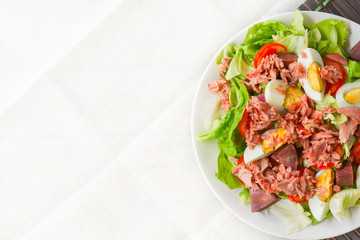 Top view tuna salad with boiled egg, tomato slice, sweet potato and lettuce on white dish with copy space. Healthy food for loose weight, high fiber and low fat.