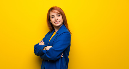 Young redhead woman with trench coat with arms crossed and happy