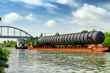 Heavy oversized chemical apparatus is transported by river transport through the shipping channel...