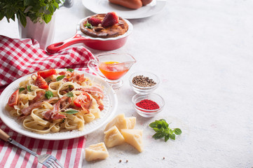 Classic pasta Carbonara, with bacon, egg, Parmesan cheese and Basil on a light background. Pieces of cheese and spices lying on the table next. Copy space.