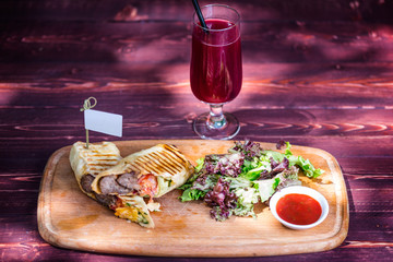 Healthy shawarma sandwich with beef, green salad, sauce and lemonade. On the cutting wooden board, and wooden background.