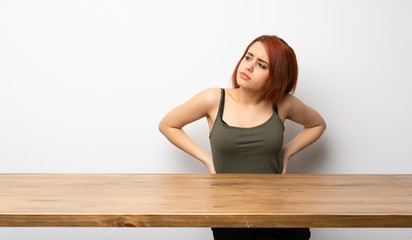 Fototapeta na wymiar Young redhead woman at desk suffering from backache for having made an effort