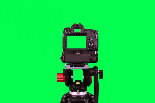 Dslr camera with green screen on the tripod isolated on green background. The chromakey. Green screen.