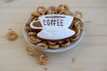 Bagels and gingerbread in the form of a cup with coffee are on a wooden table..