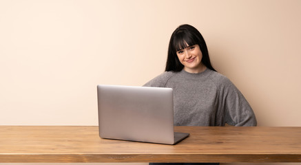 Young woman working with her laptop posing with arms at hip and smiling