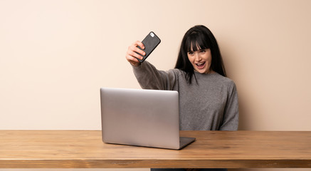 Young woman working with her laptop making a selfie