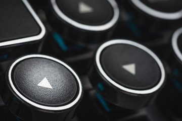 An extreme close-up or macro shot of a round directional arrow key on a vintage-inspired retro-style clicky black-and-silver metal typewriter keyboard.