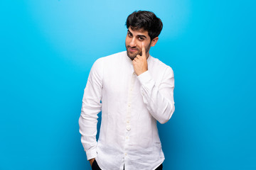 Young man over isolated blue wall looking to the front