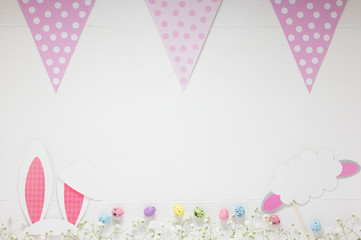 Mockup of White Festive Wooden Board with Easter Decorations along Lane of Flowers and Pink Flags Polka Dot Pattern. Concept: Happy Easter Empty Note.