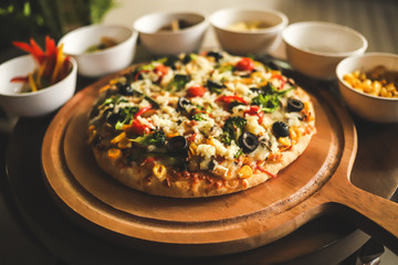 Italian fully loaded veg cheese Pizza on the table with toppings on the side